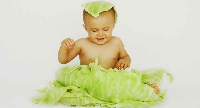 Ребенок и свежие листья капусты