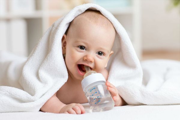 Младенец пьет воду из бутылочки